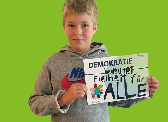 Junge mit Schild in der Hand Demokratie bedeutet Freiheit für ALLE.
