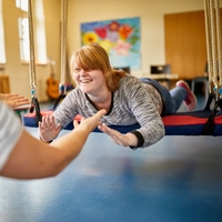 Während der Mototherapie liegt ein Mädchen bäuchlings auf einer großen Schaukel