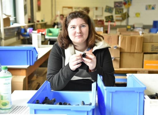 Junge Frau hält einen Kunstoffteil in den Händen