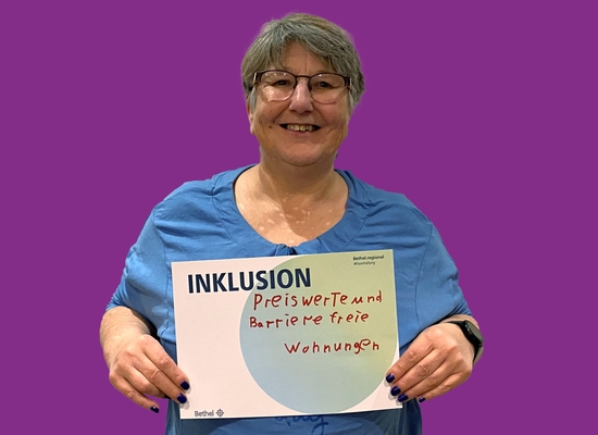 Frau mit Schild in der Hand Inklusion Preiswerte und Barrierefreie Wohnungen.