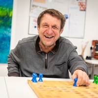 Ein Mann sitzt am Tisch in der Begegnungsstätte Hövelhof und spielt Mensch ärgere dich nicht.