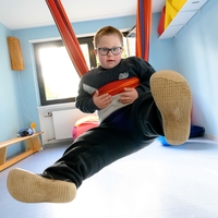 In Bethel Regional Haus am Funkturm in Dortmund hängt ein Junge mit seinen beiden armen auf einer Hängeschaukel