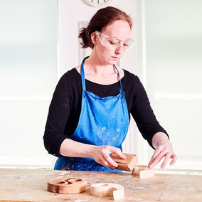 Bethel - Tagesgestaltung: Frau mit Schutzbrille schleift Holz