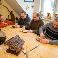 Drei Klienten werden in der Tagesstruktur Bad Lippspringe beim Arbeiten mit Holz von einer Mitarbeiterin angeleitet.