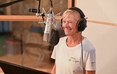 Eine Person bei der Gesangsaufnahme im Studio am Mikrofon