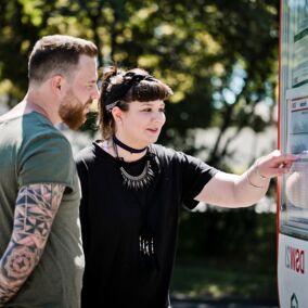 Junge Frau und junger Mann schauen sich den Anfahrtsplan des Busses
