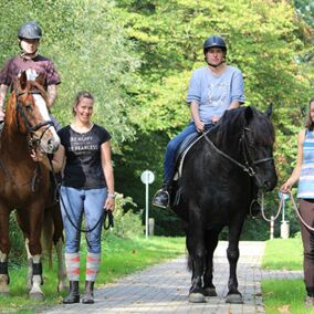 Therapeutisches Reiten: Gruppe von Betreuern und Klienten auf Pferden