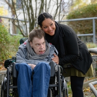 In Bethel Regional Haus am Lohbach in Dortmund sind eine Frau und ein Mann auf dem Rollstuhl am lächeln und schauen nach rechts