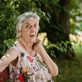Ältere Dame sitzt in einem grünen Umfeld