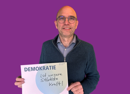 Mann mit Schild in der Hand Demokratie ist unsere stärkste Kraft!