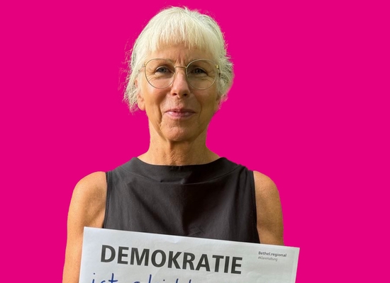 Frau mit Schild in der Hand Demokratie ist gleichberechtigter Zugang zu einem selbstbestimmten Leben.
