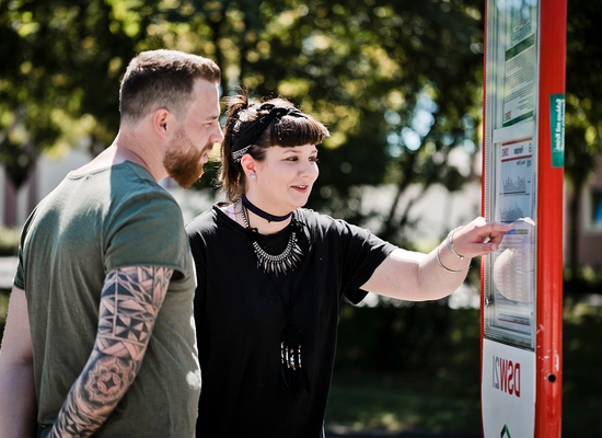 Junge Frau und junger Mann schauen sich den Anfahrtsplan des Busses