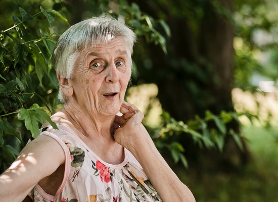 Ältere Dame sitzt in einem grünen Umfeld