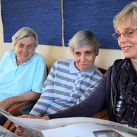 3 Personen schauen auf einen Zeitungsartikel in der "Neuen Schmiede".