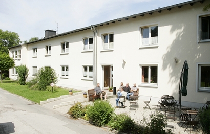 Menschen sitzen zusammen im Garten im Drevermannstift in Gevelsberg von Bethel.regional mit Wohnangeboten für Wohnungslose.