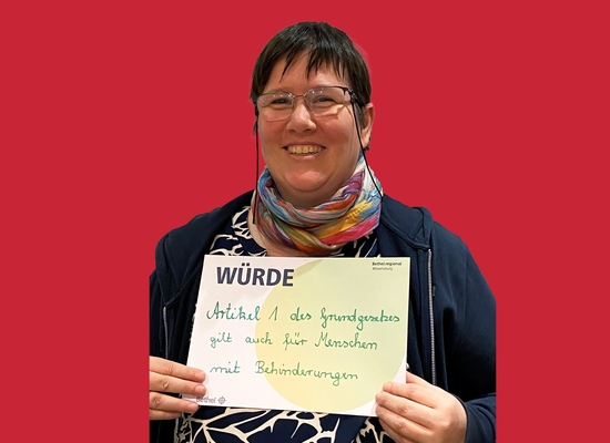 Frau mit Schild in der Hand Würde Artikel 1 des Grundgesetzes gilt auch für Menschen mit Behinderungen.