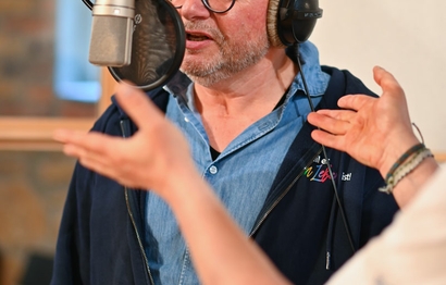 Eine Person bei der Aufnahme im Studio am Mikrofon